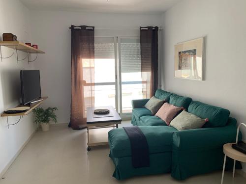 a living room with a green couch and a television at Mirador de la ría, Isla Cristina in Isla Cristina