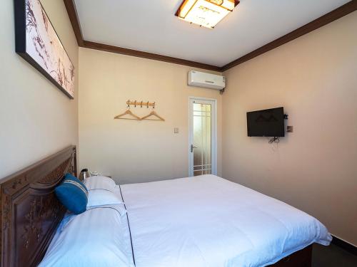 1 dormitorio con 1 cama blanca y TV en Dong Li Guest House en Miyun