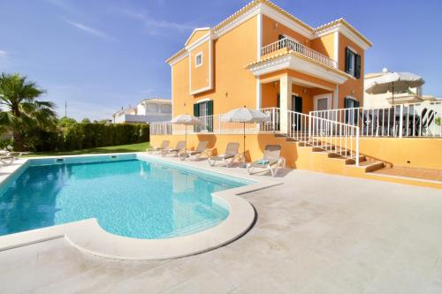 a villa with a swimming pool in front of a house at Villa Rosa - with private pool in Alcantarilha