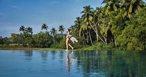 a woman walking across a body of water at Alila Diwa Goa - A Hyatt Brand in Majorda