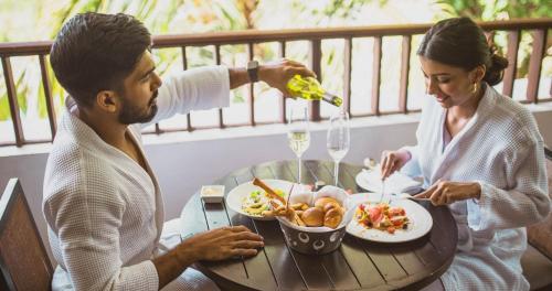 a man and woman sitting at a table eating food at Alila Diwa Goa - A Hyatt Brand in Majorda