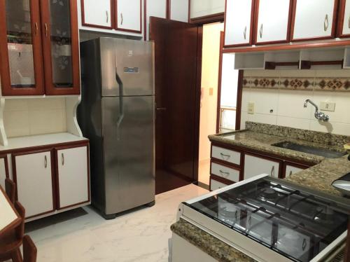 uma cozinha com um frigorífico de aço inoxidável e armários em Apartamento solar vitória regia - Frente Mar na Praia Grande