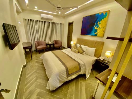 a hotel room with a bed and a table and chairs at Shelton's Ambassador in Islamabad
