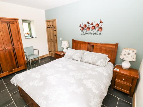 a bedroom with a white bed and a chair at Trewrach Cottage in Newport Pembrokeshire