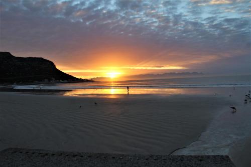 a person standing on the beach at sunset at South Peninsula Beach Apartment in Cape Town