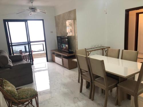 uma sala de estar com uma mesa de jantar e cadeiras em Apartamento solar vitória regia - Frente Mar na Praia Grande