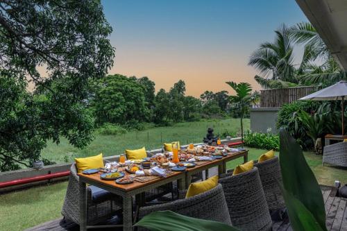 un lungo tavolo in legno con sedie e cibo sopra di Baale Resort Goa ad Arpora