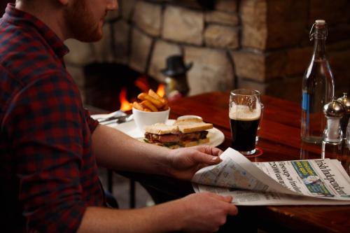 a man sitting at a table with a sandwich and a drink at Horse & Jockey Hotel in Horse and Jockey