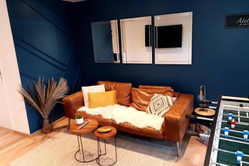 - un salon avec un canapé brun et un mur bleu dans l'établissement Villa Auxerre luxe Piscine Intérieure proche Paris sans Vis-à-vis, à Auxerre
