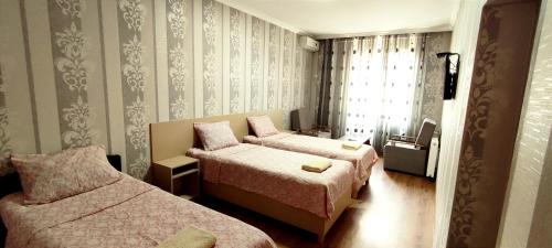 a hotel room with two beds and a window at Hotel VENUS in Tbilisi City