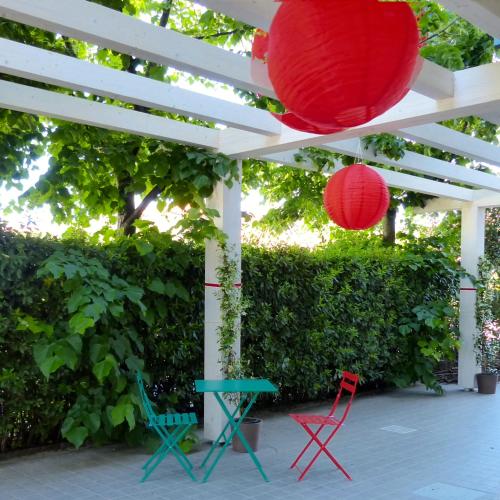 a patio with red lanterns and chairs under a white pergola at Ostello Meet Gardalake Hostel in Peschiera del Garda