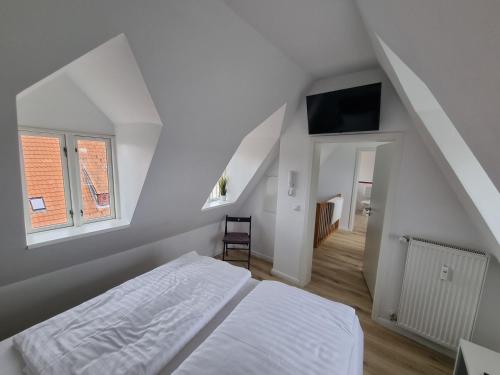 a white bedroom with a bed and a tv at Nikolai Appartements in Rostock