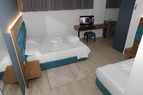 a room with two beds and a desk and a bed at Domus Hotel & Apartments in Shëngjin