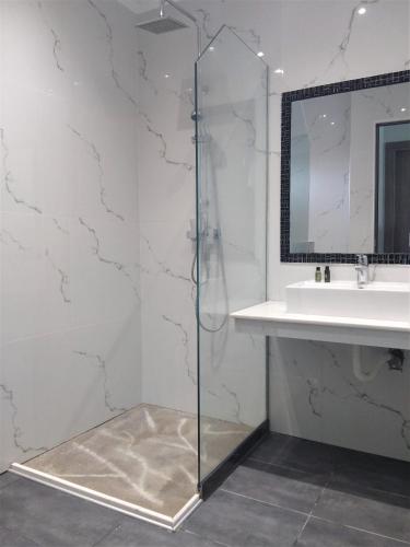 a glass shower in a bathroom with a sink at Hill Sun Luxury Suites in Nea Iraklia
