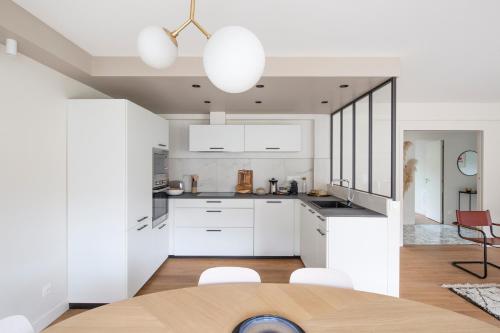 uma cozinha com armários brancos e uma mesa e cadeiras em L'Eden - Appartement familial au pied du Thabor em Rennes