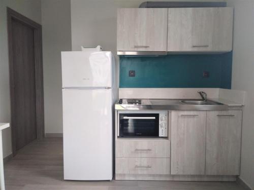 a kitchen with a white refrigerator and a sink at Hill Sun Luxury Suites in Nea Iraklia