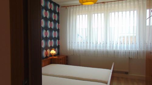 um quarto com uma cama e uma janela com uma cortina de janela em Ferienwohnung Ernst 10 em Gelenau