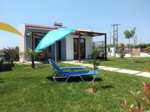 a blue chair and an umbrella in the grass at Hill Sun Luxury Suites in Nea Iraklia