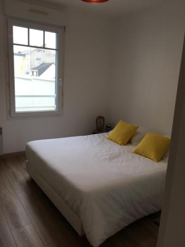 - une chambre avec un lit blanc et 2 oreillers jaunes dans l'établissement Cap'tain Kipper , vue mer, 2 chambres , garage fermé , Wimereux, à Wimereux