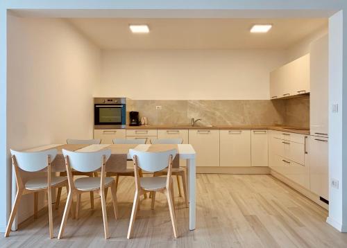 een keuken met een houten tafel en witte stoelen bij Apartments Kaldana in Rab