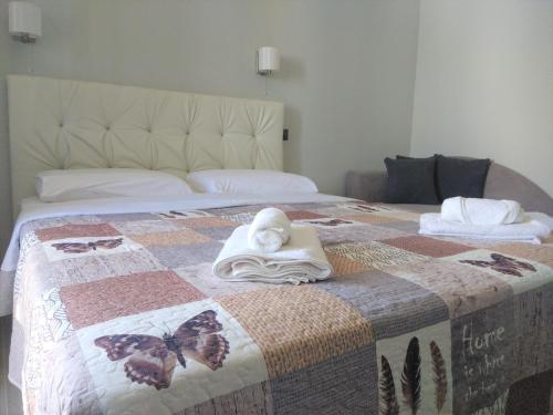 a bed with a butterfly quilt and towels on it at Hill Sun Luxury Suites in Nea Iraklia
