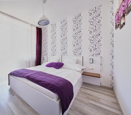 a bedroom with a bed with a purple blanket at Apartman Rubin in Sárvár