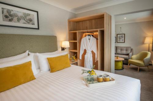 a hotel room with a bed with a suit on a rack at Horwood House Hotel in Milton Keynes