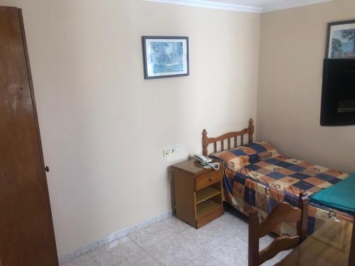 Habitación pequeña con cama, escritorio y TV. en HOSTAL ALGECIRAs, en Algeciras