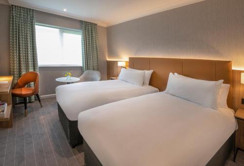 a hotel room with two beds and a desk at Horwood House Hotel in Milton Keynes