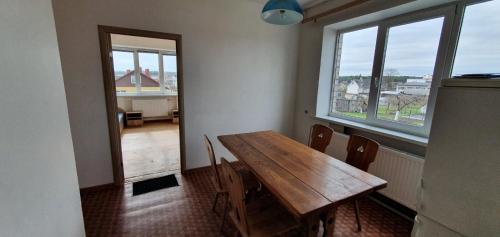 a dining room with a wooden table and two windows at Darbuotojų apgyvendimas Karmėlavoje in Karmėlava