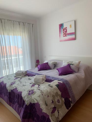 ein Schlafzimmer mit einem Bett mit einer lila und weißen Decke in der Unterkunft Bela Baïa in Salir de Porto