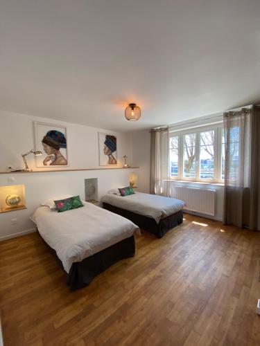 Habitación con 2 camas, suelo de madera y ventanas. en CHARNER centre gare 2 chambres 100m2 parking, en Saint-Brieuc