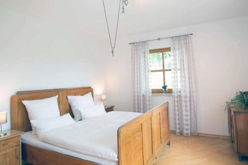 um quarto com uma cama com lençóis brancos e uma janela em Ferienwohnung Miedl em Hauzenberg
