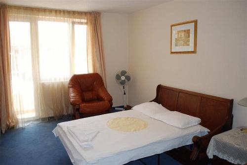 a bedroom with a bed and a chair and a window at Italia Hotel in Nesebar