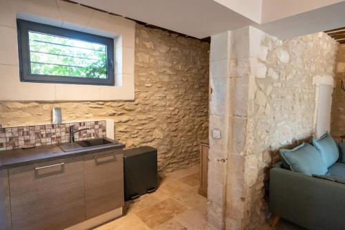 - une cuisine avec un mur en pierre et un évier dans l'établissement Maison de ville provençale - tout confort, à Saint-Rémy-de-Provence