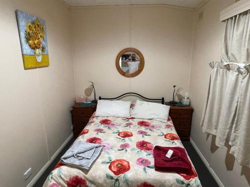 a bedroom with a bed with a floral bedspread at Homely Cottage in Hawker