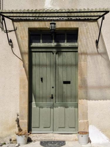 Gîte Moishan في Mouchan: باب أخضر على جانب المبنى