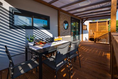 a patio with a table and chairs on a deck at Mobile Home Vodice 27 in Vodice