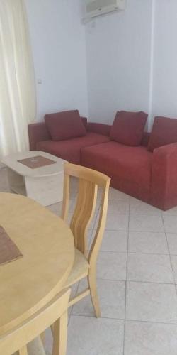 een woonkamer met een tafel en een rode bank bij Kamelia Garden - sunny beach in Sunny Beach