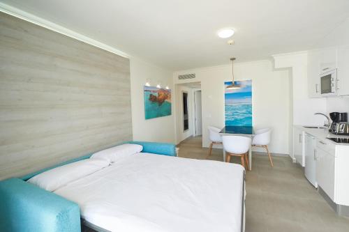 a bedroom with a white bed and a kitchen at Suite Hotel Montana Club in Puerto del Carmen