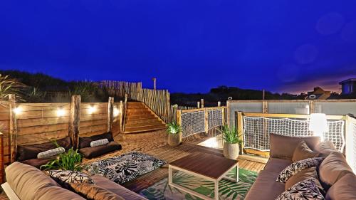 a patio with a couch and a wooden deck at night at sangatte " Les Terrasses" maison front de mer Les pieds dans l'eau pleine de charme Cap Blanc Nez Côte d'Opale in Sangatte
