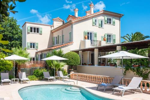 a villa with a swimming pool with chairs and umbrellas at Mas Djoliba in Antibes