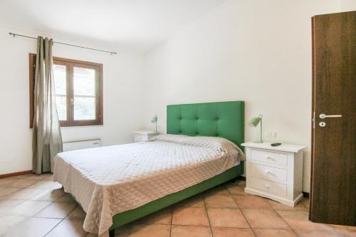 a bedroom with a bed with a green headboard and a window at Lake & Country Holidays in Bussolengo