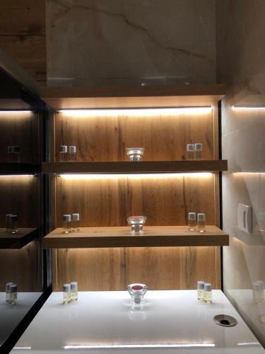 a bathroom with a sink with glasses on a shelf at Lux Apartman 33 in Kragujevac