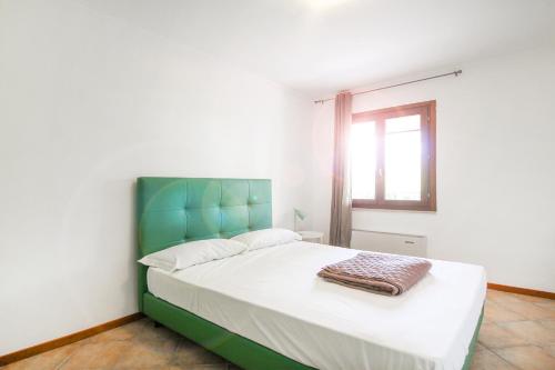 una camera da letto con letto con testiera verde e finestra di Lake & Country Holidays a Bussolengo