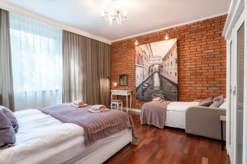 a bedroom with two beds and a brick wall at Lavender Cosy Apartment in Gdańsk