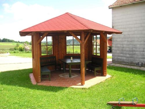 a wooden gazebo with a table and chairs at Petersimmerhof in Taching am See