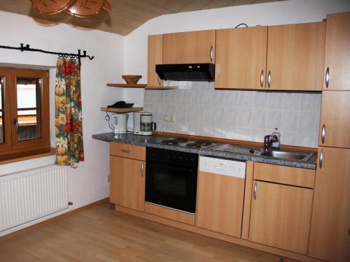 a kitchen with wooden cabinets and a sink and a stove at Petersimmerhof in Taching am See