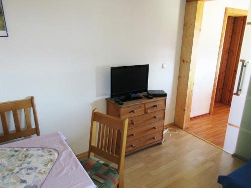 a living room with a television on a dresser with a bed at Petersimmerhof in Taching am See