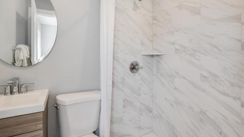 a white bathroom with a toilet and a shower at A Wave Inn - Montauk in Montauk